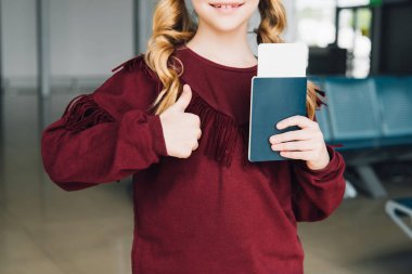havaalanında başparmak yukarı gösteren pasaport ve hava bileti ile preteen çocuk kırpılmış görünümü