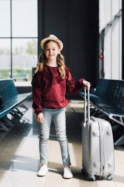 havaalanında bekleyen salonda bavul ile gülümseyen preteen çocuk