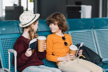 sevimli preteen çocuklar oturmak içinde bekleme salon ile kahve için gitmek ve pasaport