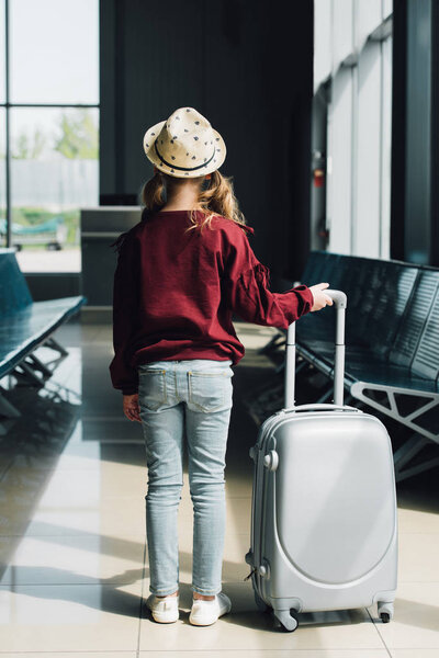 Вид на подростка с чемоданом в зале ожидания в аэропорту
