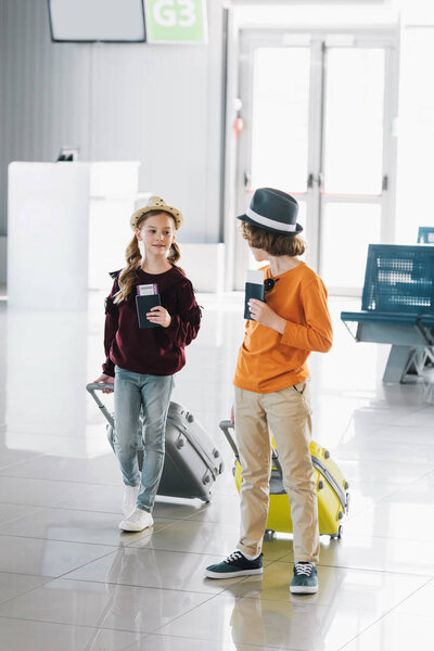 preteen children with suitcases, air tickets and passports in waiting hall