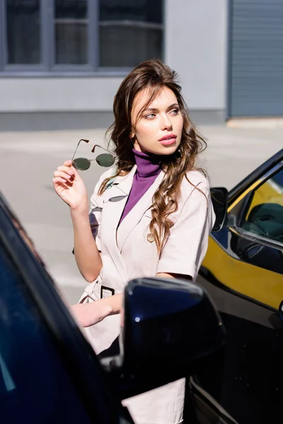 Selectieve Focus Van Ernstige Jonge Vrouw Bedrijf Zonnebrillen Buurt Van — Stockfoto