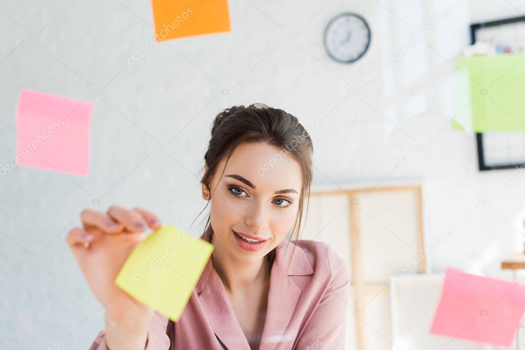 selective focus of young woman hanging yellow sticky note 