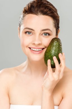 gri izole organik ve olgun avokado tutan gülümseyen çekici kadın 