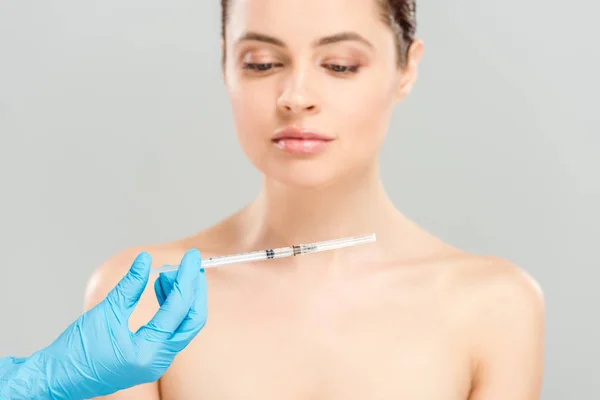 麻醉师拿着注射器在裸体妇女附近隔离在灰色的裁剪视图 — 图库照片