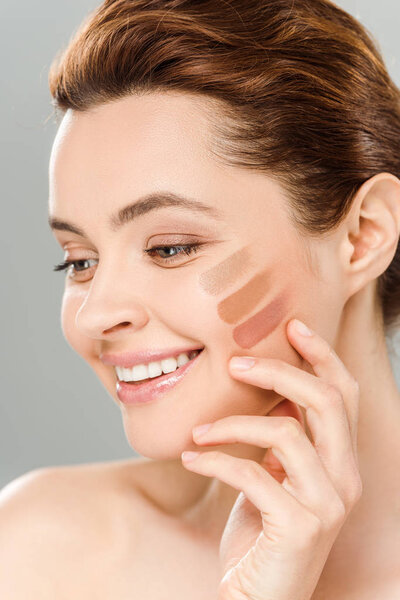 cheerful woman with eye shadow brown palette on face isolated on grey