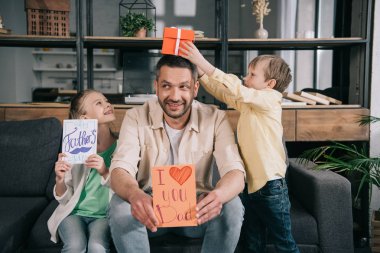 happy children with fathers day gifts having fun with father holding greeting card with i love you dad inscription and heart symbol clipart