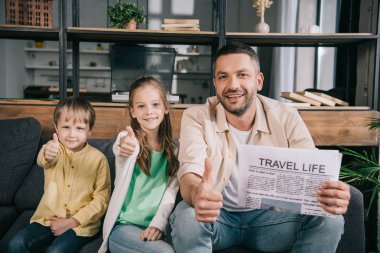 mutlu aile baba seyahat yaşam gazetesi tutarken başparmak gösteren