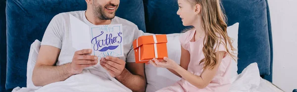 Panoramic Shot Adorable Daughter Presenting Gift Box Smiling Father Lying — Stock Photo, Image