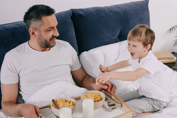 Vrolijke Vader Zoon Ontbijten Tijdens Een Verblijf Bed Samen — Stockfoto