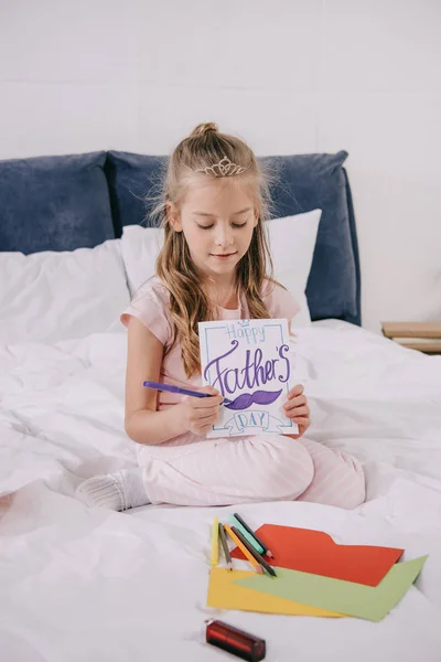 Adorable Child Drawing Fathers Day Greeting Card While Sitting Bedding — Stock Photo, Image