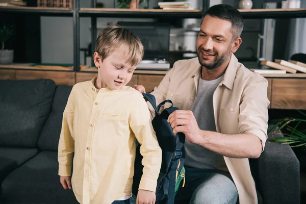Uśmiechnięty Tata Pomaga Cute Boy Oddanie Plecak Domu — Zdjęcie stockowe