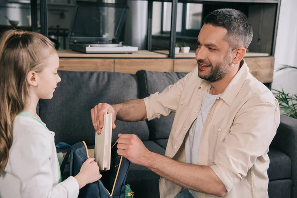 Handsome Smiling Man Helping Daughter Packing Book Backpack — Stock Photo, Image