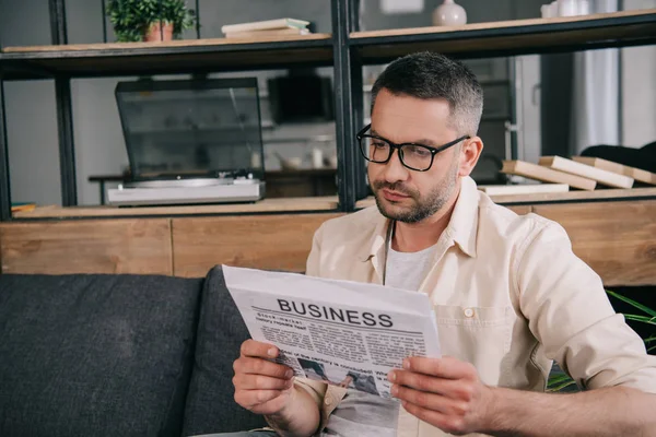 Stilig Man Glasögon Läsa Business Tidning När Sitter Soffan Hemma — Stockfoto