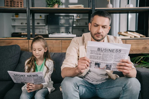 集中した父と娘は 自宅でスポーツニュースやビジネス新聞を読んで — ストック写真
