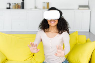 vr kulaklık neşeli afrikalı amerikalı kadın kanepede oturuyor