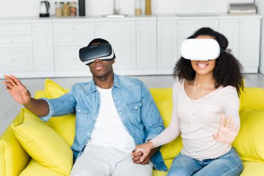 vr kulaklık içinde afrikalı-amerikalı çift kanepede oturan