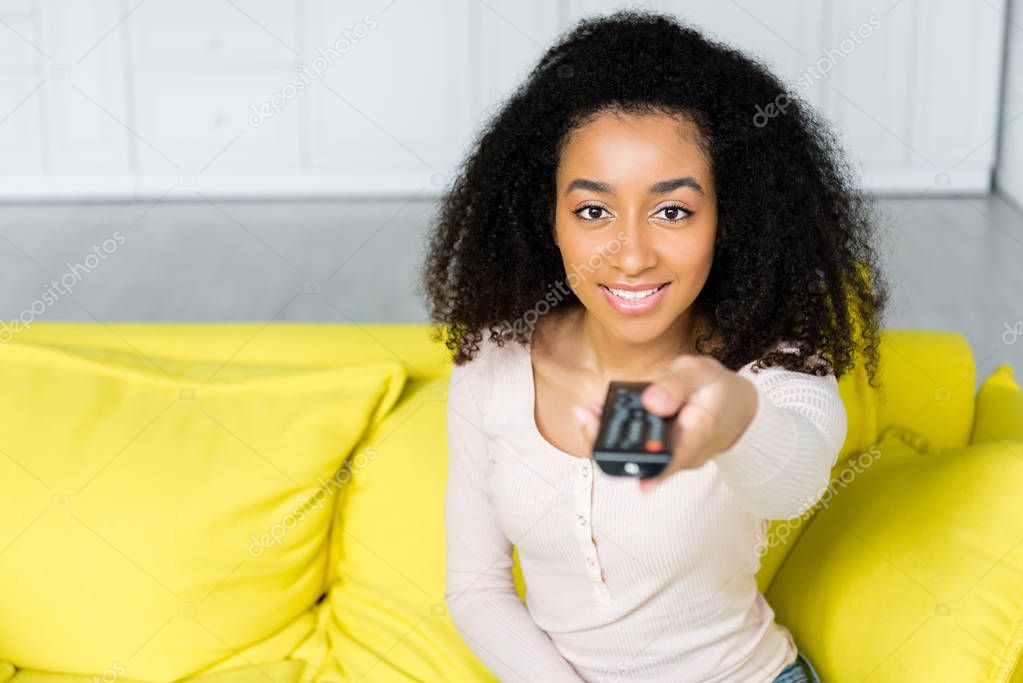 high angle view of happy african american woman holding remote controller in hand