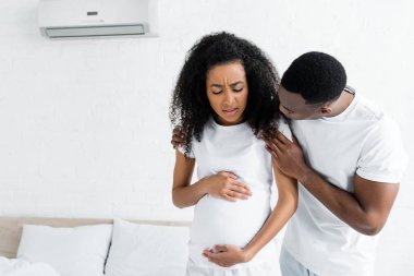 odada endişeli ve hamile karısı sarılma afrikalı amerikalı adam