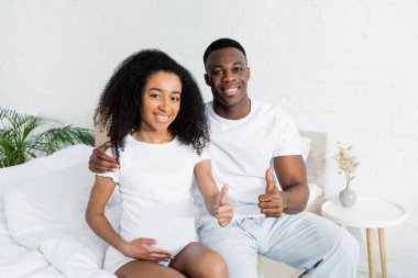 yatakta oturan ve başparmak kadar gesturing afrikalı-amerikalı çift