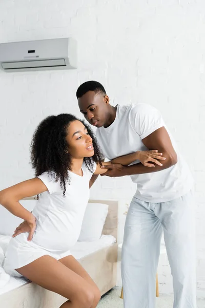 妊娠中の妻を助けるアフリカ系アメリカ人男性 ベッドから立ち上がる — ストック写真
