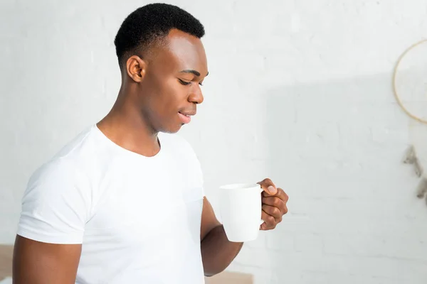 Hombre Afroamericano Feliz Sosteniendo Taza Blanca Mano Pie Habitación Blanca — Foto de Stock