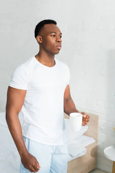 Serieuze Afro Amerikaanse Man Staande Witte Kamer Holding Cup Met — Stockfoto