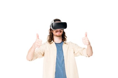 VR kulaklık kullanan genç bir adam kameraya baş parmağını gösteriyor.