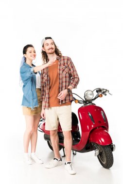 beautiful girl pointing with hand and young man looking away, standing near red scooter isolated on white clipart