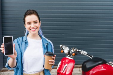kırmızı scooter yanında duran güzel kız ön görünümü, kahve ve akıllı telefon ile kağıt fincan tutarak