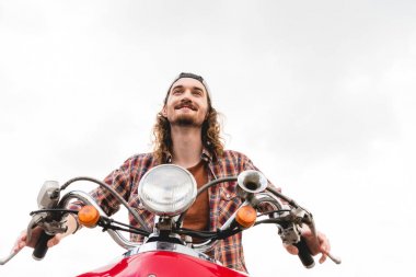 kırmızı scooter üzerinde ridding ve ileriye dönük genç adam düşük açı görünümü