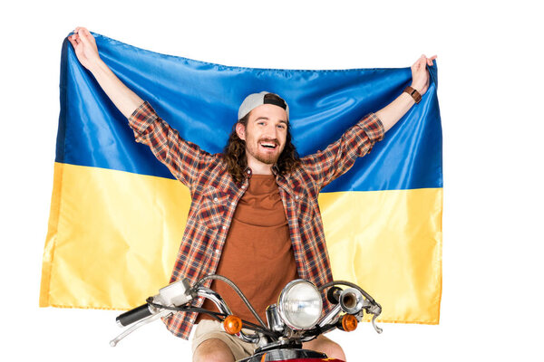 young man sitting on red scooter, holding Ukrainian flag in air isolated on white