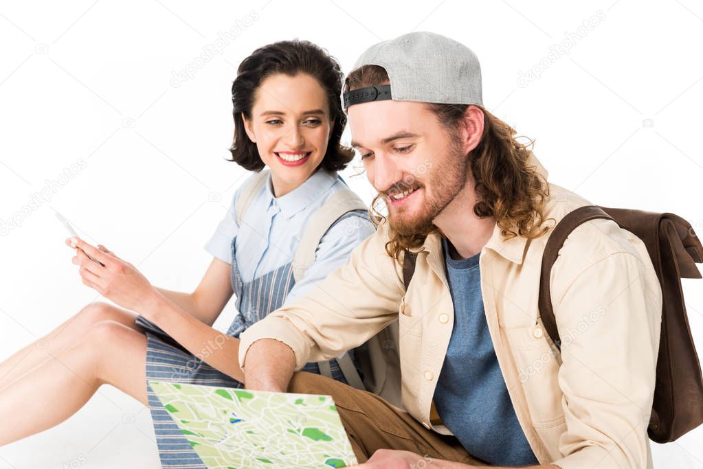 beautiful girl smiling while young man looking at map isolated on white