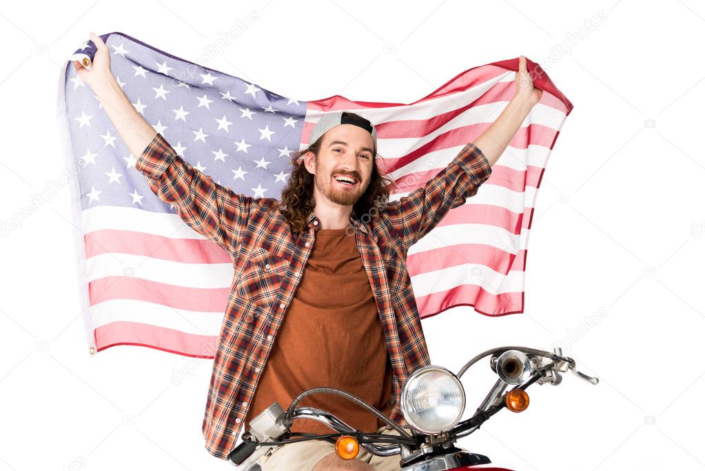 young man sitting on red scooter, smiling and holding American flag on air isolated on white