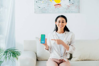 KYIV, UKRAINE - APRIL 26, 2019: Attractive latin woman holding smartphone with Twitter app on screen.  clipart