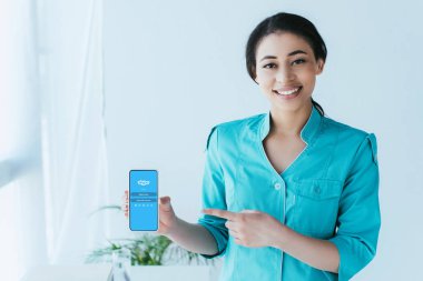 Kiev, Ukrayna - 26 Nisan 2019: Ekranda Skype uygulaması ile akıllı telefon parmak ile işaret güzel latin doktor.