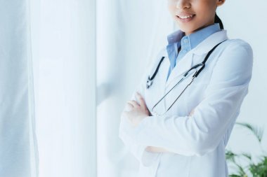 çapraz kolları ile pencerenin yanında duran stetoskop ile genç latin doktor kırpılmış atış
