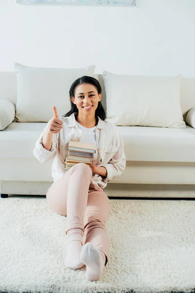 Cheerful Latin Woman Showing Thumb Holding Stack Books While Sitting — Stock Photo, Image