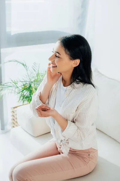 Cheerful Latin Woman Talking Smartphone Looking Away While Sitting Couch — Stock Photo, Image