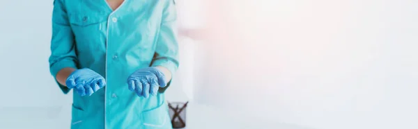 Panoramatický Záběr Ošetřovatelky Modrých Uniformích Latexové Rukavice Držící Otevřené Dlaně — Stock fotografie