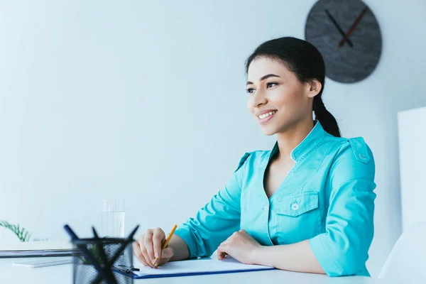 Beautiful Latin Doctor Writing Clipboard While Sitting Workplace Looking Away — Stock Photo, Image