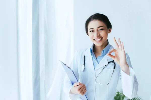 Hermoso Médico Latino Sonriendo Cámara Mientras Muestra Gesto Bien Sujetando — Foto de Stock