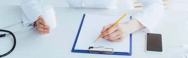 Panoramic Shot Young Doctor Writing Clipboard While Sitting Workplace Holding — Stock Photo, Image