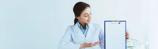 Plano Panorámico Bonito Médico Latino Señalando Con Mano Portapapeles Con — Foto de Stock