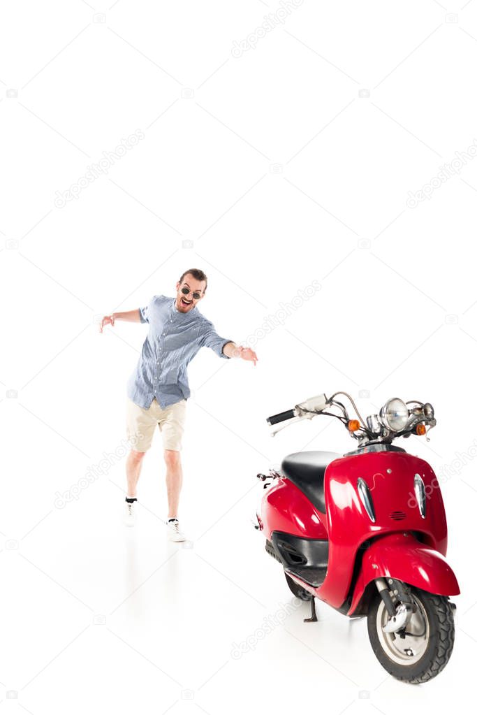 handsome stylish young man trying to grab red scooter isolated on white