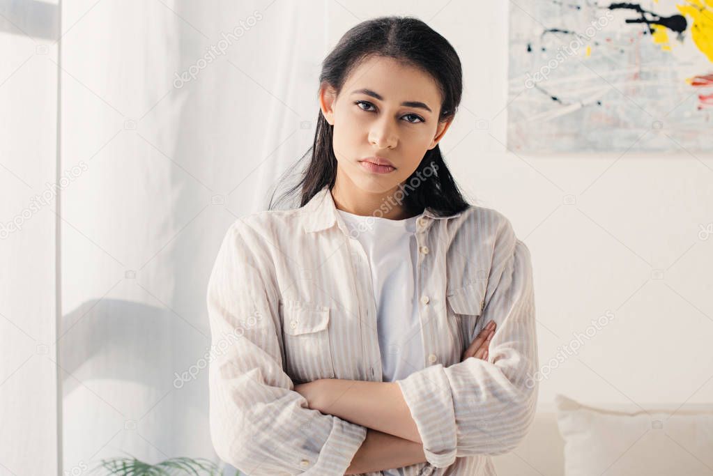 serious latin woman standing with crossed arms and looking at camera