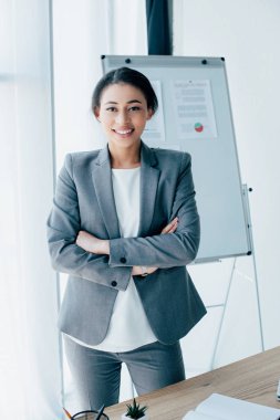 güzel latin iş kadını kolları çapraz ile ayakta ve kamera gülümseyerek