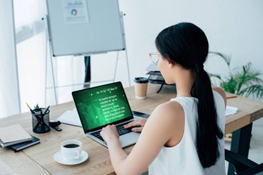 Genç Latin iş kadını laptopunu kullanarak iş yerinde kahve içerken ekranda mesaj bilgisini kullanıyor.