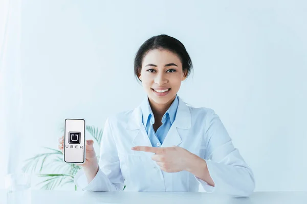乌克兰 2019年4月26日 美丽的拉丁医生用手指指着智能手机与优步应用程序在屏幕上 — 图库照片