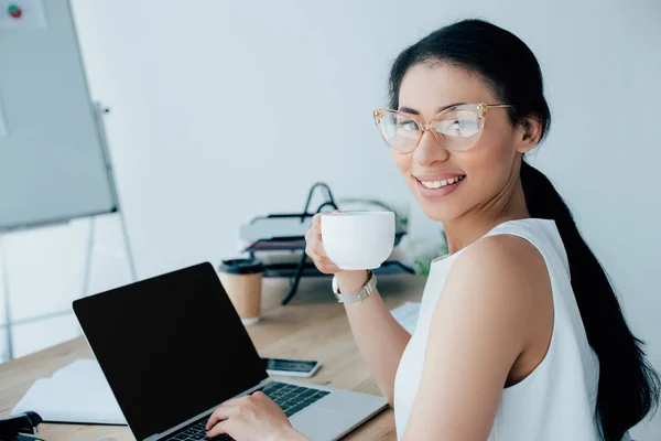 Mulher Negócios Latina Alegre Segurando Xícara Café Usando Laptop Enquanto — Fotografia de Stock